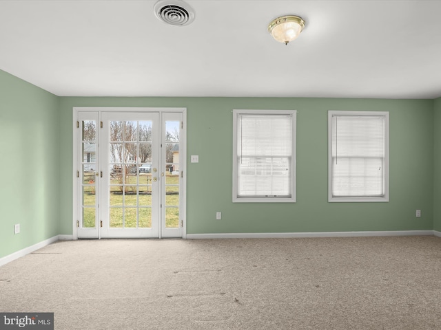 carpeted spare room with visible vents and baseboards