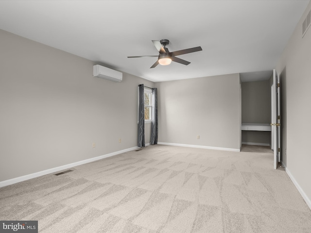 carpeted empty room with visible vents, a wall mounted AC, a ceiling fan, and baseboards