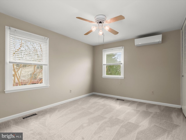 spare room with light carpet, a wall unit AC, visible vents, and baseboards