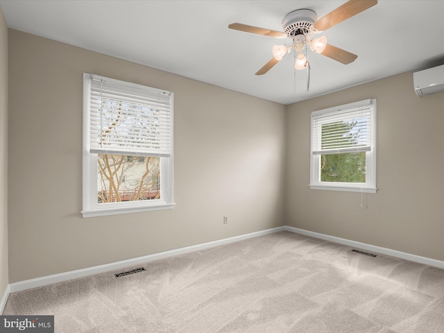 carpeted spare room featuring an AC wall unit, a ceiling fan, visible vents, and baseboards