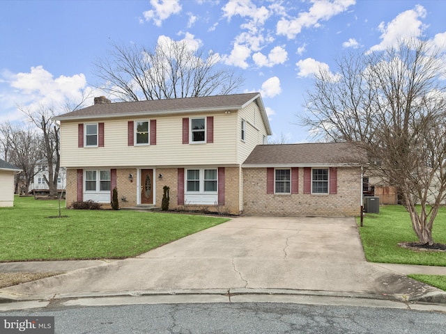 colonial home with driveway, brick siding, and a front lawn