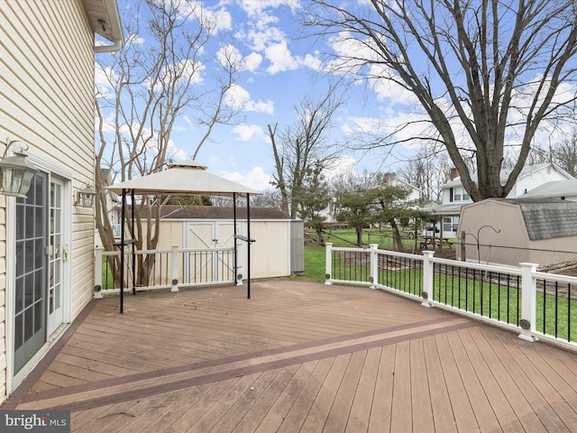 wooden terrace with an outdoor structure, fence, a gazebo, a yard, and a shed