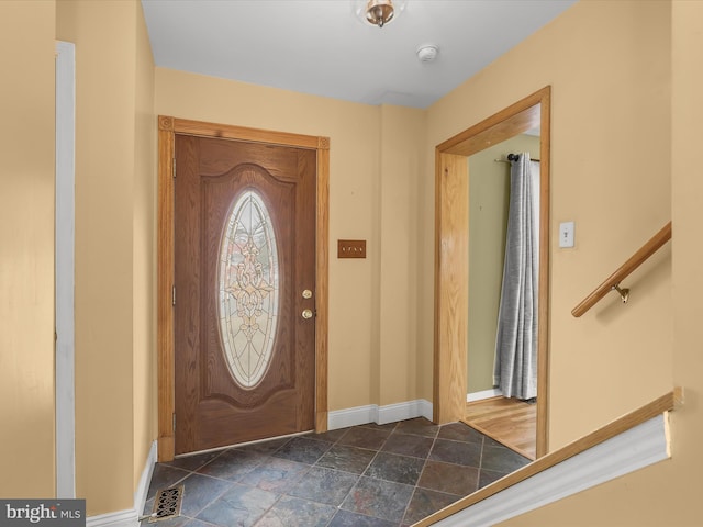 foyer entrance featuring stone finish floor and baseboards