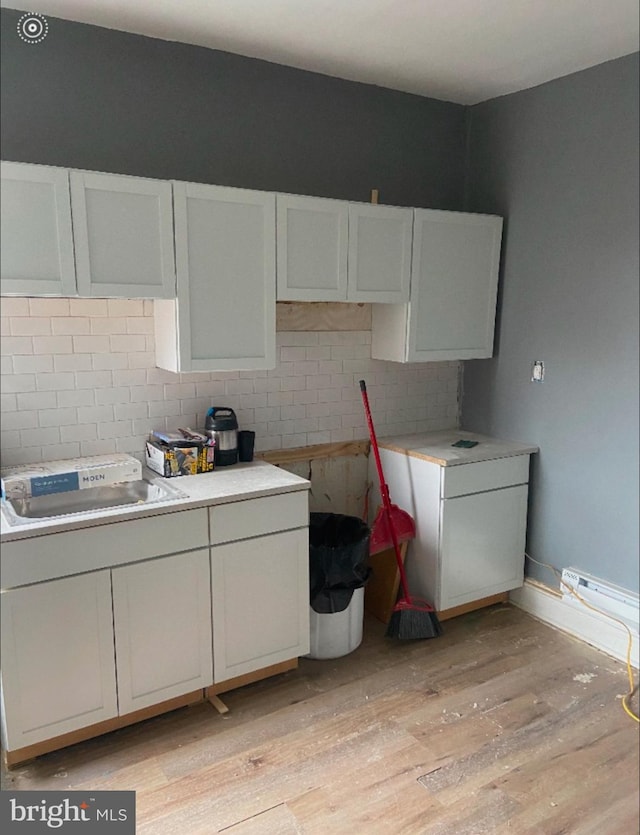 kitchen featuring light hardwood / wood-style floors, tasteful backsplash, white cabinetry, and sink