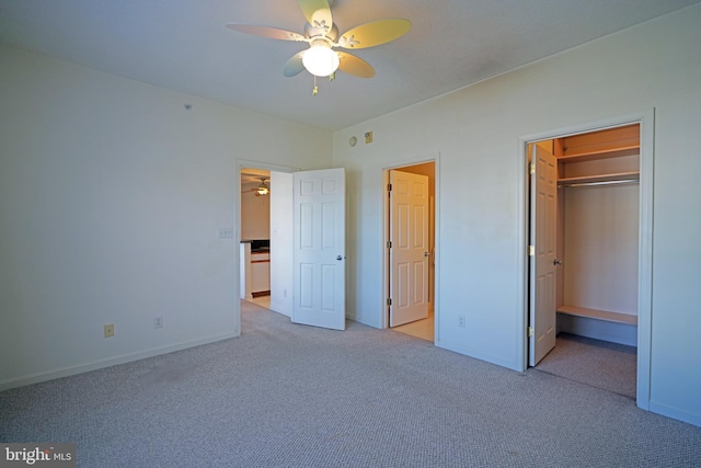 unfurnished bedroom with ceiling fan, light colored carpet, a walk in closet, and a closet