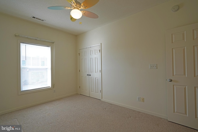 unfurnished bedroom with light carpet, a closet, and ceiling fan