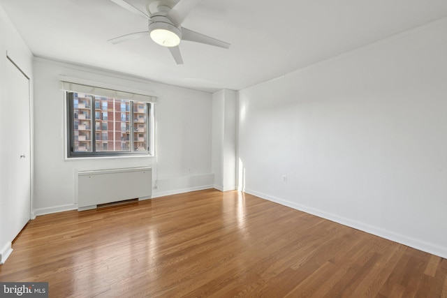 spare room with hardwood / wood-style floors, radiator heating unit, and ceiling fan