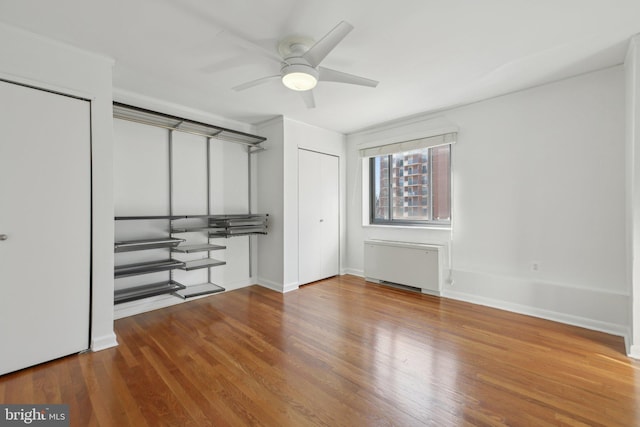 unfurnished bedroom featuring radiator, hardwood / wood-style floors, and ceiling fan