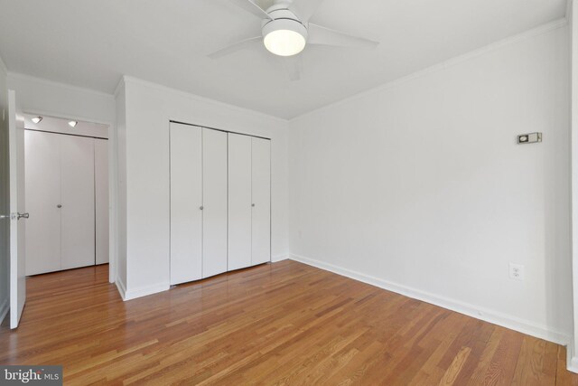 unfurnished bedroom with wood-type flooring, ornamental molding, ceiling fan, and a closet