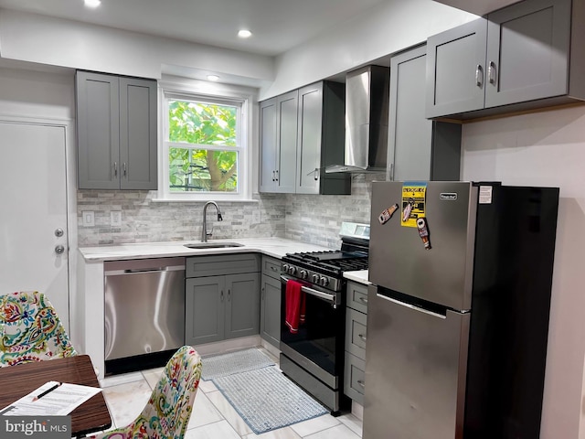 kitchen with gray cabinetry, wall chimney range hood, sink, appliances with stainless steel finishes, and light tile patterned flooring