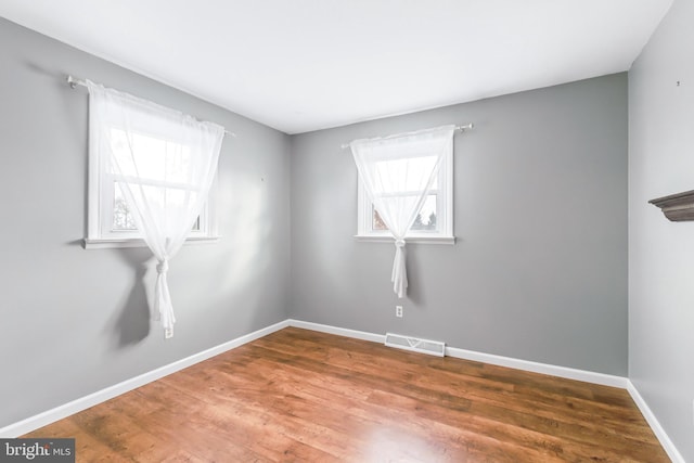 unfurnished room with wood-type flooring and a healthy amount of sunlight