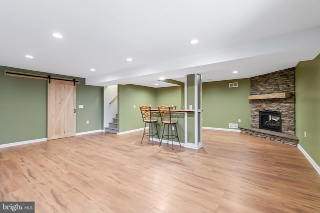 interior space featuring a barn door, a fireplace, and light hardwood / wood-style flooring