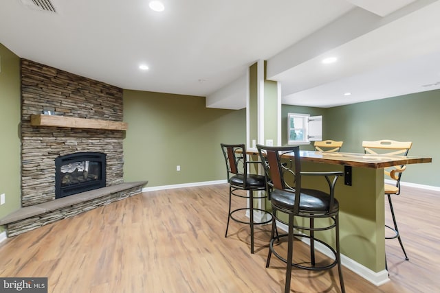 kitchen with a stone fireplace, a breakfast bar, and light wood-type flooring