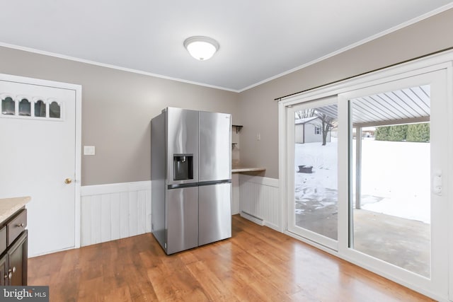 kitchen featuring stainless steel fridge, light hardwood / wood-style floors, and ornamental molding