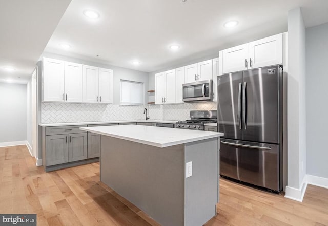 kitchen with white cabinetry, a kitchen island, light hardwood / wood-style floors, and appliances with stainless steel finishes