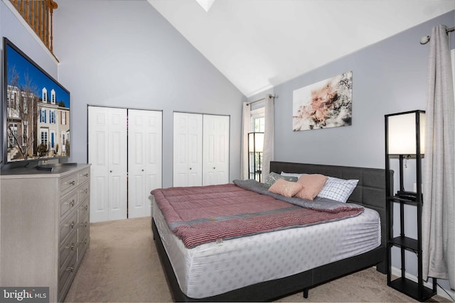 bedroom featuring high vaulted ceiling, two closets, and light carpet