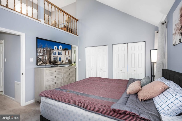 carpeted bedroom with multiple closets and high vaulted ceiling