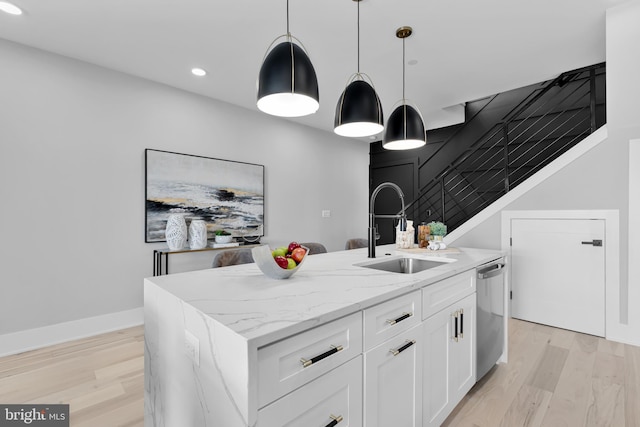 kitchen with pendant lighting, white cabinets, dishwasher, and a kitchen island with sink