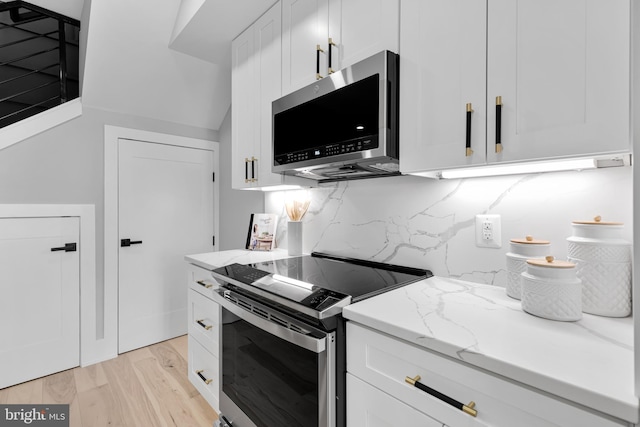 kitchen featuring stainless steel appliances, white cabinetry, light stone counters, and light hardwood / wood-style flooring