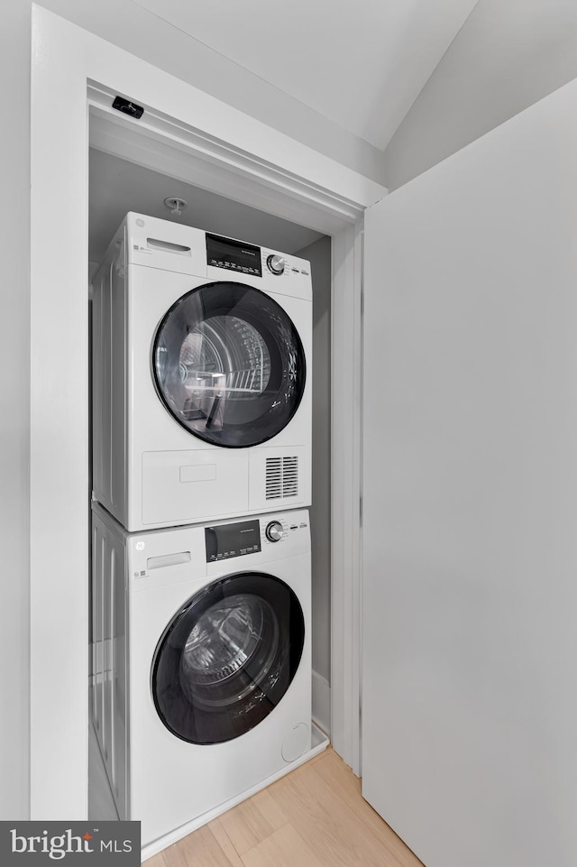 laundry area featuring light hardwood / wood-style floors and stacked washing maching and dryer