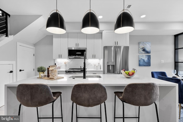 kitchen with pendant lighting, white cabinetry, light stone counters, decorative backsplash, and stainless steel appliances