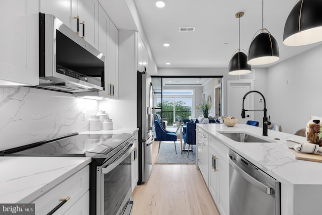 kitchen featuring sink, pendant lighting, white cabinets, and stainless steel appliances