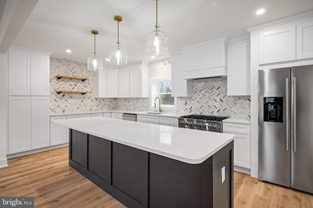 kitchen with stainless steel appliances, white cabinetry, hanging light fixtures, and light hardwood / wood-style flooring