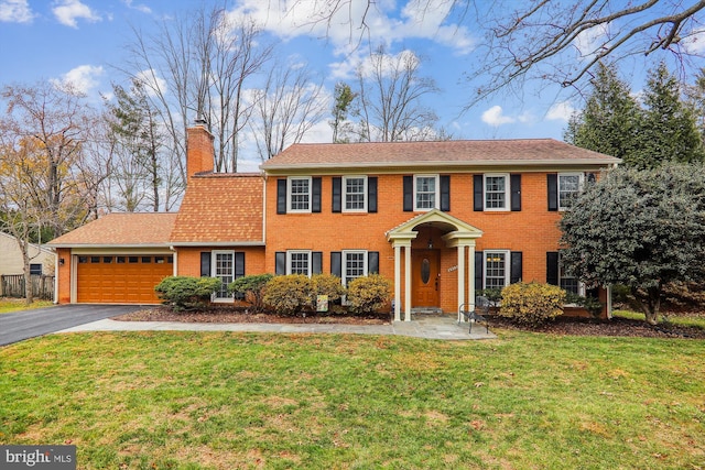 colonial-style house featuring a garage and a front lawn