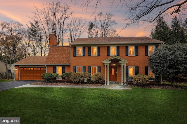 colonial home with a lawn and a garage