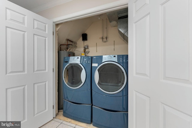 laundry room with light tile patterned floors, crown molding, and washing machine and clothes dryer