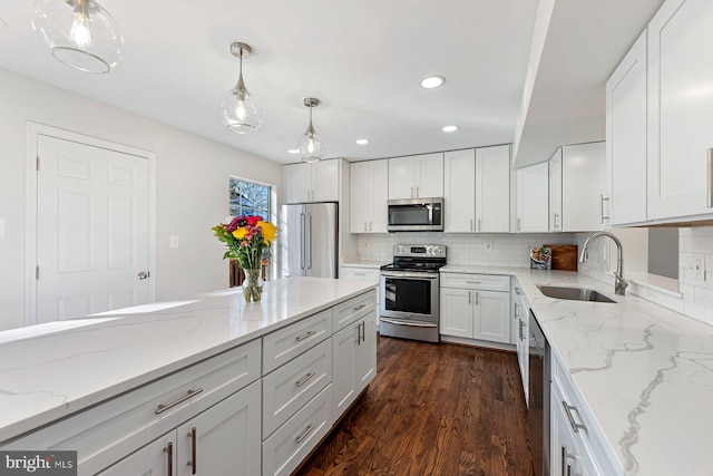 kitchen featuring pendant lighting, appliances with stainless steel finishes, sink, tasteful backsplash, and white cabinetry