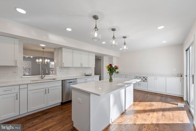 kitchen with dishwasher, a kitchen island, white cabinetry, sink, and light stone counters