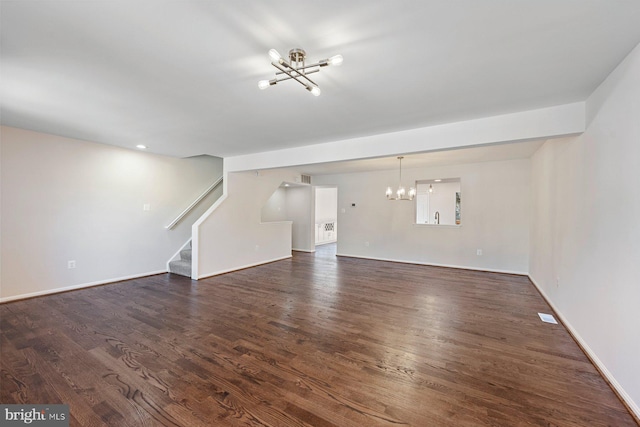 unfurnished living room with a chandelier and dark hardwood / wood-style floors