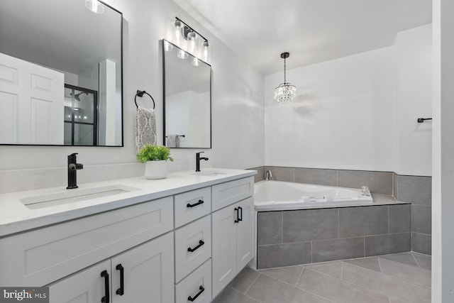 bathroom featuring tile patterned flooring, a relaxing tiled tub, and vanity