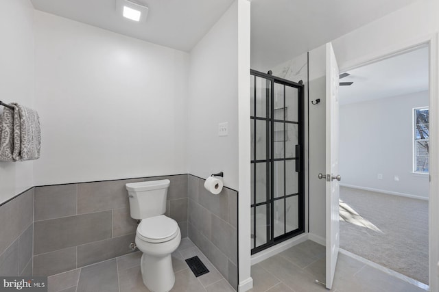 bathroom with toilet, walk in shower, tile walls, and tile patterned flooring