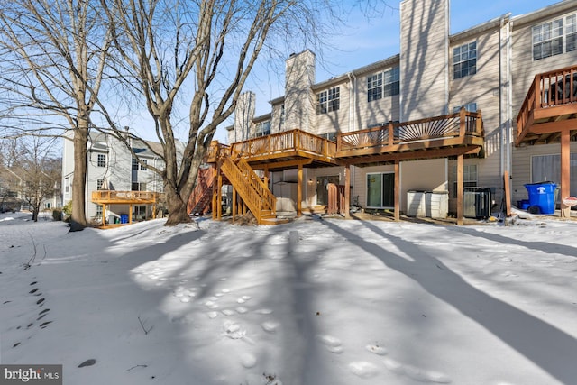 snow covered house featuring cooling unit and a deck