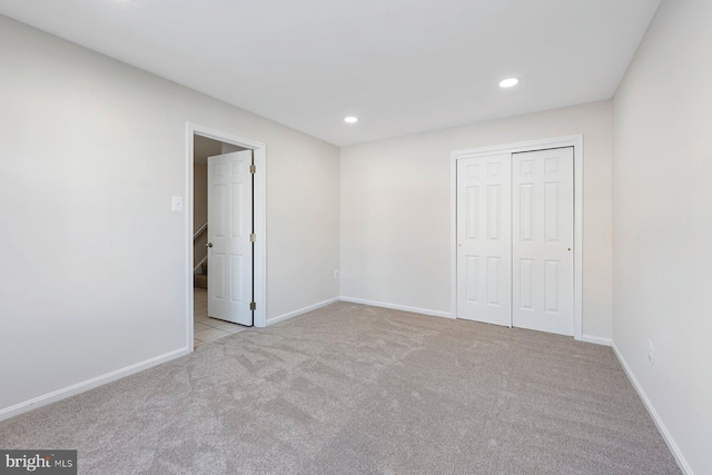 unfurnished bedroom featuring a closet and light carpet