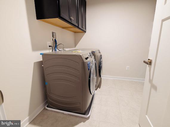 clothes washing area with cabinets and washer and clothes dryer