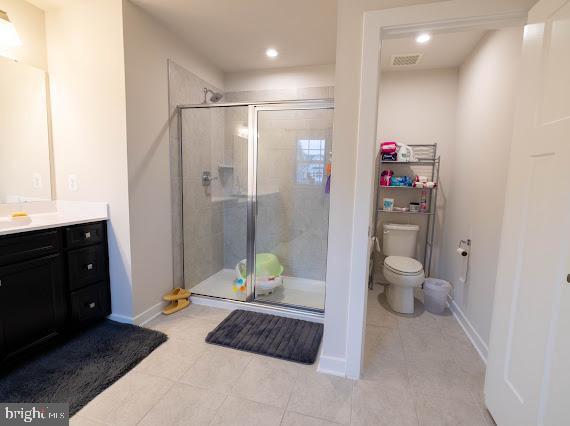 bathroom featuring tile patterned flooring, vanity, toilet, and an enclosed shower