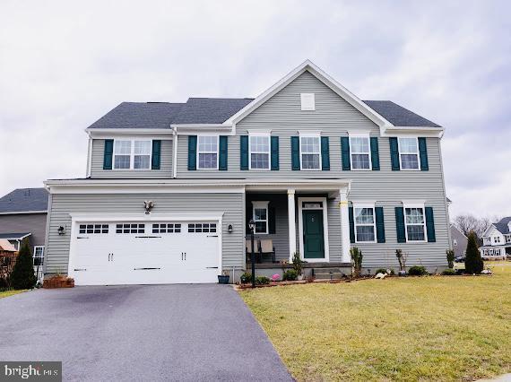 view of front of property with a porch, a garage, and a front lawn