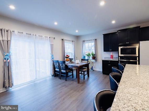 kitchen featuring a kitchen bar, dark hardwood / wood-style flooring, stainless steel appliances, and light stone countertops