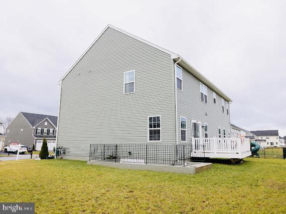 back of property featuring a wooden deck and a lawn