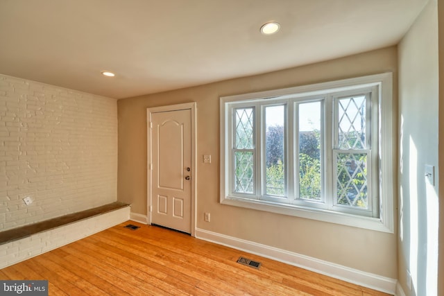 entryway featuring light hardwood / wood-style floors and brick wall