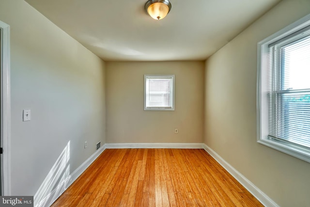 empty room with light hardwood / wood-style floors and a healthy amount of sunlight