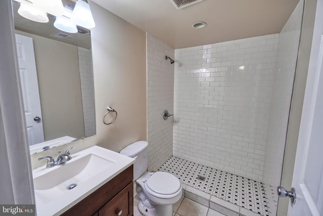 bathroom with tiled shower, vanity, tile patterned floors, and toilet