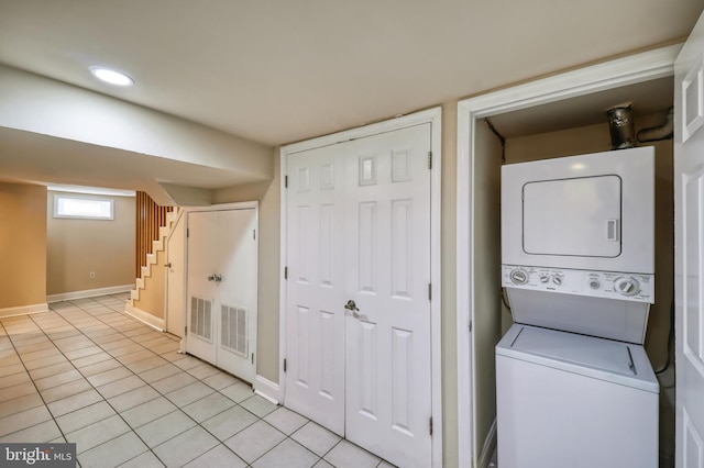 laundry room featuring stacked washing maching and dryer and light tile patterned floors