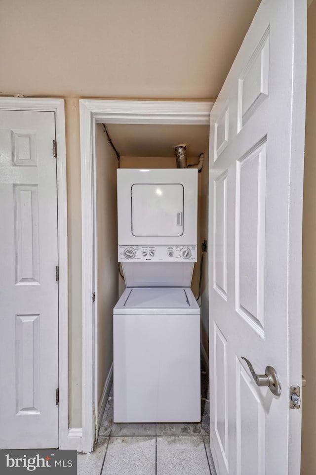 laundry area featuring light tile patterned floors and stacked washing maching and dryer