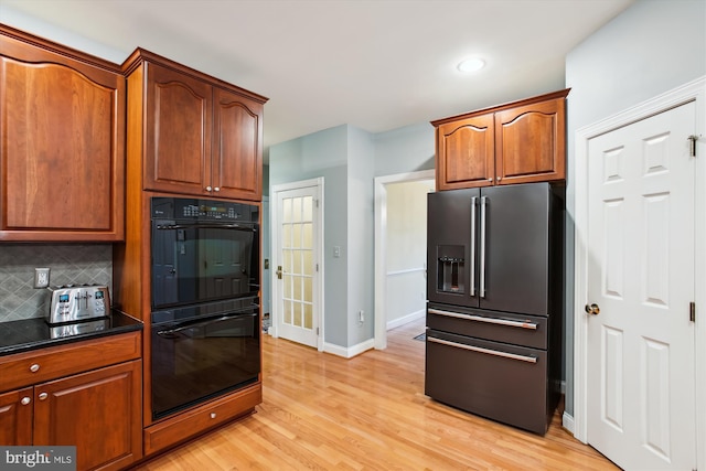 kitchen with tasteful backsplash, high end fridge, light hardwood / wood-style flooring, and black double oven