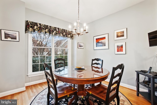 dining space with hardwood / wood-style floors and an inviting chandelier