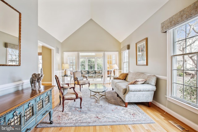 living room with light hardwood / wood-style floors, lofted ceiling, and a wealth of natural light